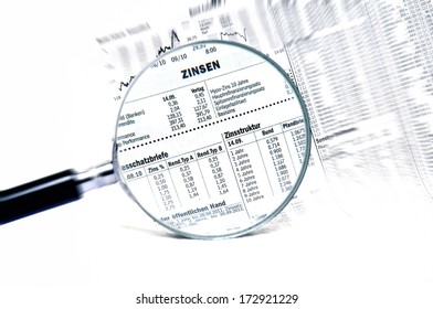 Stock market charts behind a magnifying glass