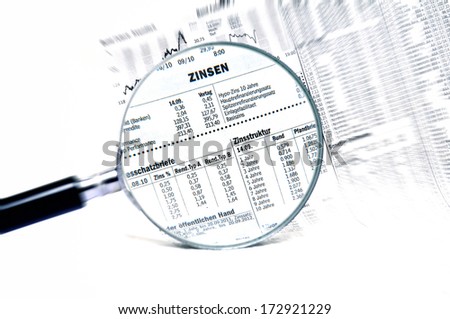 Stock market charts behind a magnifying glass