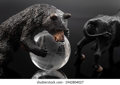 Stock market correction and the end of the bull market concept with a bear (symbol of economic contraction) taking over the globe( symbolizing the global economy) isolated on black background - Shutterstock ID 1942804027