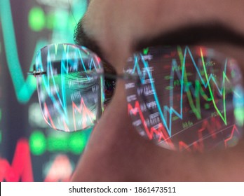 Stock market data on computer screen being reflected onto glasses.