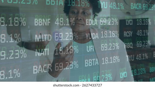 Stock market data processing over african american senior woman measuring her temperature at home. Global finance and covid-19 pandemic concept