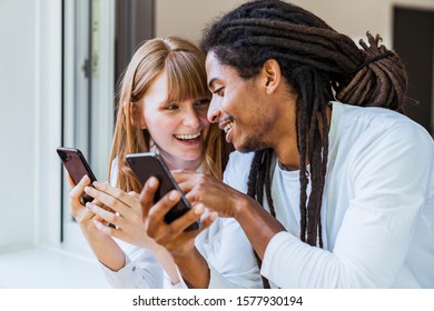 Stock photo of a black boy with dreadlocks watching the mobile and pointing to the screen of a girl's mobile next to him. Technology and lifestyle - Powered by Shutterstock