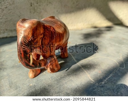 Stock photo of brown color  elephant statue or idol carved out of wooden  kept on floor under bright sunlight at Gulbarga, Karnataka, India. selective focus, blur background.