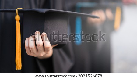 Stock photo closed-up and selective focus of the university graduates in graduation gown holding graduation hat in the commencement day