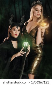 Stock Photo - Maleficent Demonic And Wicked Witch With An Apple. Girls Dressed As A Fairy Witch In Raincoat And With Horns