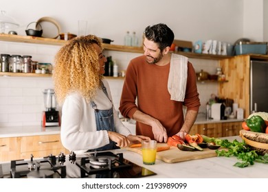 Stock photo of a middle aged woman and man preparing food in a kitchen. They are chopping up some vegetables while laughing. - Powered by Shutterstock