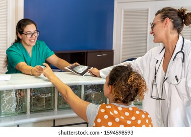 Stock Photo Of A Nurse Giving A Room Key To A Patient In A Wheelchair While A Doctor Gives Her An X-ray At A Hospital Reception