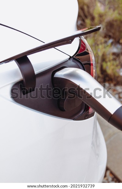 Stock photo of a plug charging a modern electric\
car or EV car in power station. Sustainable mobility and\
Eco-friendly alternative energy\
concept
