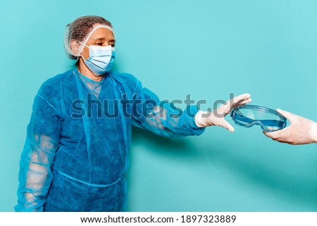 Stock photo of professional healthcare worker wearing special disposable clothes and protective glasses for covid19.