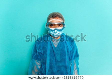 Stock photo of professional healthcare worker wearing special disposable clothes and protective glasses for covid19.
