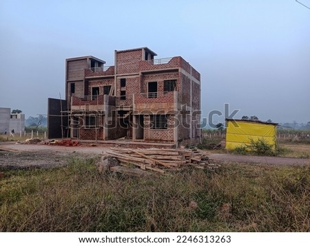 Stock photo of row house construction in the countryside area, construction material like cement bag, bamboo, etc around site. Picture captured under natural light , farmland on background at Kolhapur