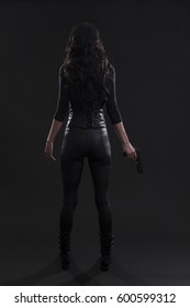 Stock photo of a sexy female assassin. Rear view with a gun.