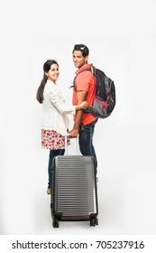 Stock Photo Showing Back Of Smart Asian Or Indian Couple Traveler With Suitcase And Hike Bag Isolated Over White Background, Going Abroad Or Within Country, Perfect Shot For Tours And Travels Company
