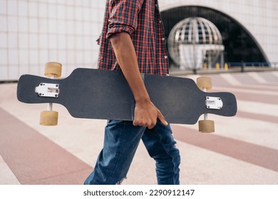 Stock photo of unrecognized skater boy walking in the city with his longboard. - Powered by Shutterstock