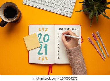 Stock Photo Of Woman Writing Goals In A 2021 New Year Notebook On Yellow Background