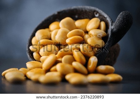 Stock photo of yellow lupini beans in a bowl isolated on black background.