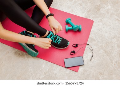 Stock photo of a young woman tying her shoelaces at home in the living room for sports - Powered by Shutterstock