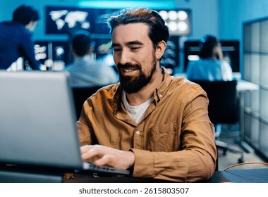 Stock trader analyzing financial data on laptop, working late in monitoring room with multiple screens displaying real-time charts and graphs. Financial investment and technology concept