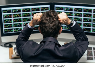 Stock trader tearing out his hair from despair, rear view
