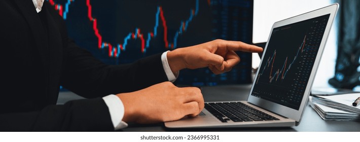 Stock trading investor finger pointing on dynamic financial data graph on monitor. Businessman or broker with analytic thinking analyzing data for stock market exchange trading company. Trailblazing - Shutterstock ID 2366995331
