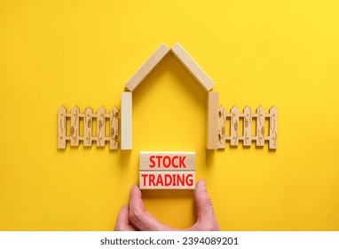 Stock trading symbol. Concept words Stock trading on beautiful wooden blocks. Beautiful yellow table yellow background. Businessman hand. House model. Business stock trading concept. Copy space. - Powered by Shutterstock