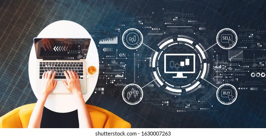 Stock trading theme with person using a laptop on a white table - Shutterstock ID 1630007263
