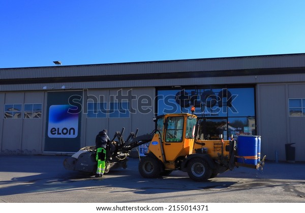 Stockholm,\
Sweden. 04-15-2022.  Driver fixing something at a tractor or\
excavator. ELON signs in the background. At Bromma Blocks, a suburb\
to the Swedish capital. Nice sunny day.\
