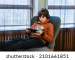 Stockholm, Sweden- 2  Jan 2022, Teenager boy wearing headset playing game on Nintendo Switch console.  Family issue is social game addicted. Teenage boy playing online game with serious face.