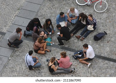 STOCKHOLM, SWEDEN - 20.09.2009 Group Of Young Students Sitting Outside In A Street On A Cobblestone Pedestrian Walking Road, Studying, Talking, Taking Notes, Counting Money. Aerial Summer Day Shot