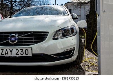 STOCKHOLM, SWEDEN - APRIL 18, 2019: White Modern Plug-in Volvo V60 Car Plugged And Charging Its Battery With Green Electricity In Scandinavian Country Sweden