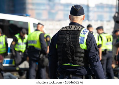 Stockholm, Sweden - August 28, 2020: A Swedish Policeman Standing Alone With His Back Turned Watching His Fellow Police Officers Working In Front Of Him.