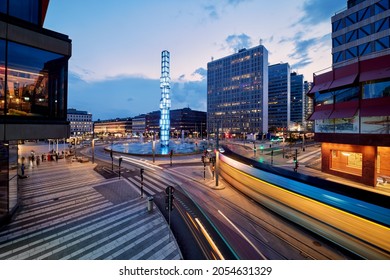 Stockholm, Sweden - Jul 28, 2021: Late Sunset View With Trams And Other Traffic Light Trail Round Serger Fountain Close To Sergels Square And Hötorget Buildings.