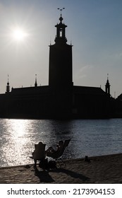 Stockholm, Sweden July 1, 2022 A Couple Is Relaxing In Beach Chairs At Sunset Overlooking Riddarfjarden And The City Hall.