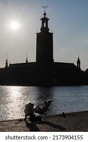 Stockholm, Sweden July 1, 2022 A Couple Is Relaxing In Beach Chairs At Sunset Overlooking Riddarfjarden And The City Hall.