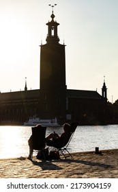 Stockholm, Sweden July 1, 2022 A Couple Is Relaxing In Beach Chairs At Sunset Overlooking Riddarfjarden And The City Hall.