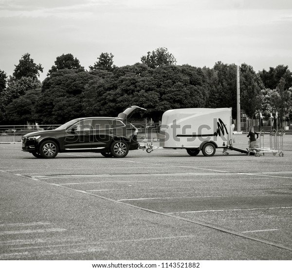STOCKHOLM, SWEDEN - JUN 7, 2018: Single mother with her\
daughter loading in the Volvo SUV car trailer good bought from IKEA\
furniture store in the wide empty parked of the Swedish furniture\
retailer -