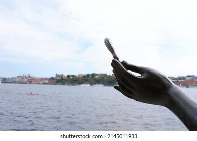 Stockholm, Sweden - June 26, 2019: Statue Of Woman Holding A Flower On The Stockholm City Hall Seafront With A View To Riddarfjärden