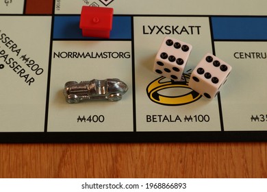 Stockholm, Sweden. May 02, 2021. Monopoly Board Game. Close Up Over The Blue Street Called Norrmalmstorg. Written In Swedish. The Metal Car Token, Double Dice And A Red Hotel. Classical Boardgame.