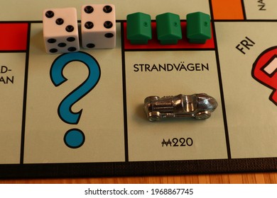 Stockholm, Sweden. May 02, 2021. Monopoly Board Game. Close Up Over The Red Street Called Strandvägen. Written In Swedish. The Metal Car Token, Double Dice And Green Houses. Classical Boardgame.