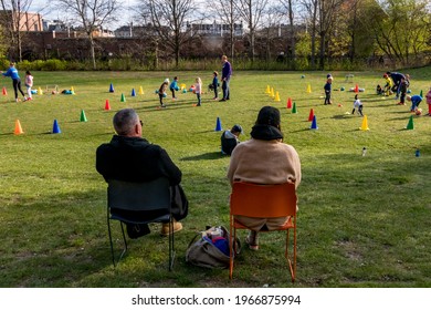 Stockholm, Sweden May 1, 2021 Parents Sitting In Lawn Chairs Watching Kids Do Soccer Practice.