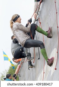 STOCKHOLM, SWEDEN - MAY 14, 2016: Two  Woman Climbing The Rampage Obstacle, Hanging In Rope  In The Obstacle Race Tough Viking Event In Sweden, May 14, 2016