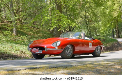 STOCKHOLM, SWEDEN - MAY 22, 2017: Red Jaguar E-Type classic car from 1965 driving on a country road in the public race Gardesloppet in the forests at Djurgarden, Stockholm, Sweden. May 22, 2017