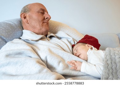 Stockholm, Sweden A  middle aged man  sleeps on the couch with his newborn granddaughter. - Powered by Shutterstock