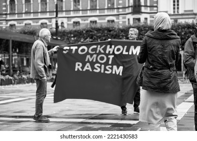 STOCKHOLM, SWEDEN - Sep 17, 2022: A Muslim Woman Standing In Front Of A Banner With Stockholm Against Racism During A Demonstration, Grayscale Shot