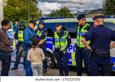 Stockholm, Sweden - September 17, 2017: Group Of Uniformed Swedish Male Police Officers Talking To A Little Dark Haired Child In The City Center