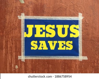Stockholm, Sweden - September 4, 2020: A small poster taped on a wall with the christian message "jesus saves" with blue background and yellow text same as the Swedish flag.