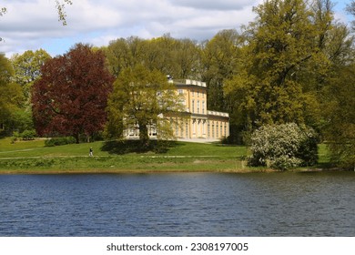 Stockholm, Sweden, with surrounding area Gustav III's Pavilion at Haga Park seen over the water in mid spring and sunny weather with clouds and fresh sprung leaves on the trees