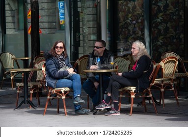 Stockholm/Sweden: May 2020: Two Women And One Man At Outdoor Sitting At A Cafe Table And Drinking And Talking In Kungsträdgården On A Spring Day During The Pandemic Outbreak Of Coronavirus.