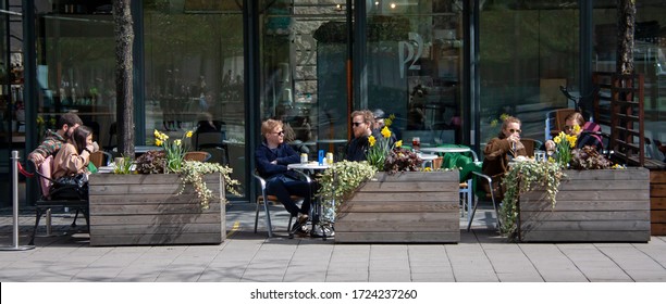 Stockholm/Sweden - May 2020 - Young People At Outdoor Sitting At A Restaurant Tables Eating, Drinking And Talking In Kungsträdgården On A Sunny Spring Day During The Pandemic Outbreak Of Coronavirus.