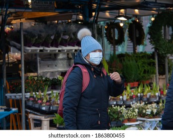 Stockholm-Sweden - Nov 2020: A Young Woman With A Protective Mask In A Blue Cap With Pompon At An Open Air Market Place, The Hötorget - Hay Square, During Pandemic Of Coronavirus. Selected Focus.